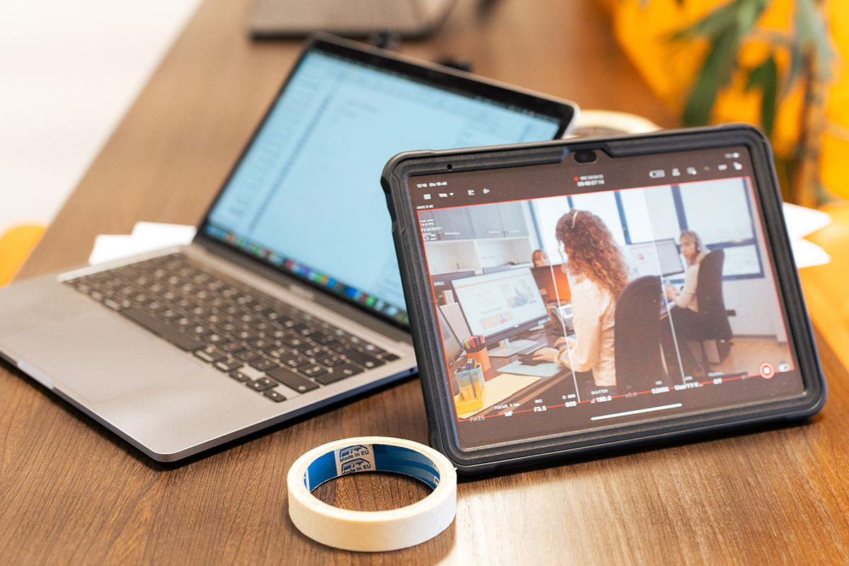 Scrivania con in primo piano un laptop e un tabket che mostra delle riprese video in corso